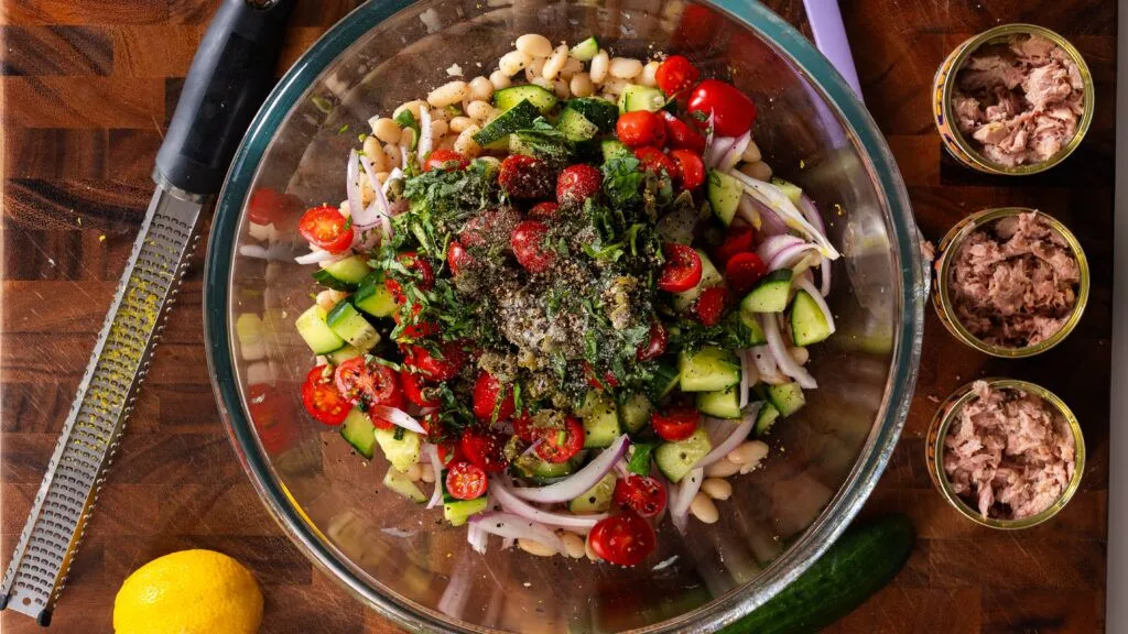 Stanley Tucci tuna bean salad ingredients in a clear serving bowl.