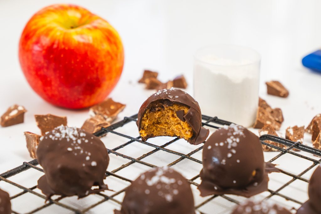 A wire rack with protein peanut butter balls. One of the balls has a bite taken out.