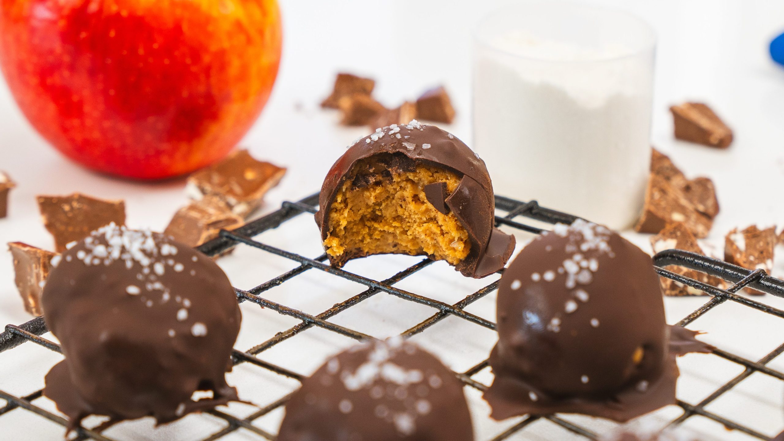 A wire rack with protein peanut butter balls. One of the balls has a bite taken out.