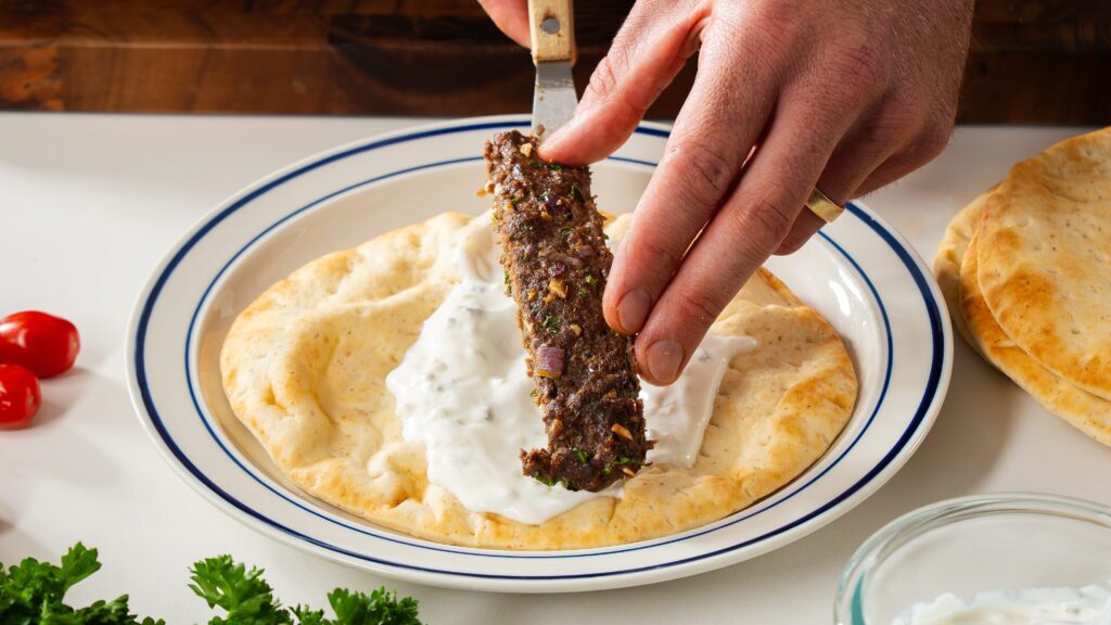 Building the pita with beef kebab and tzatziki