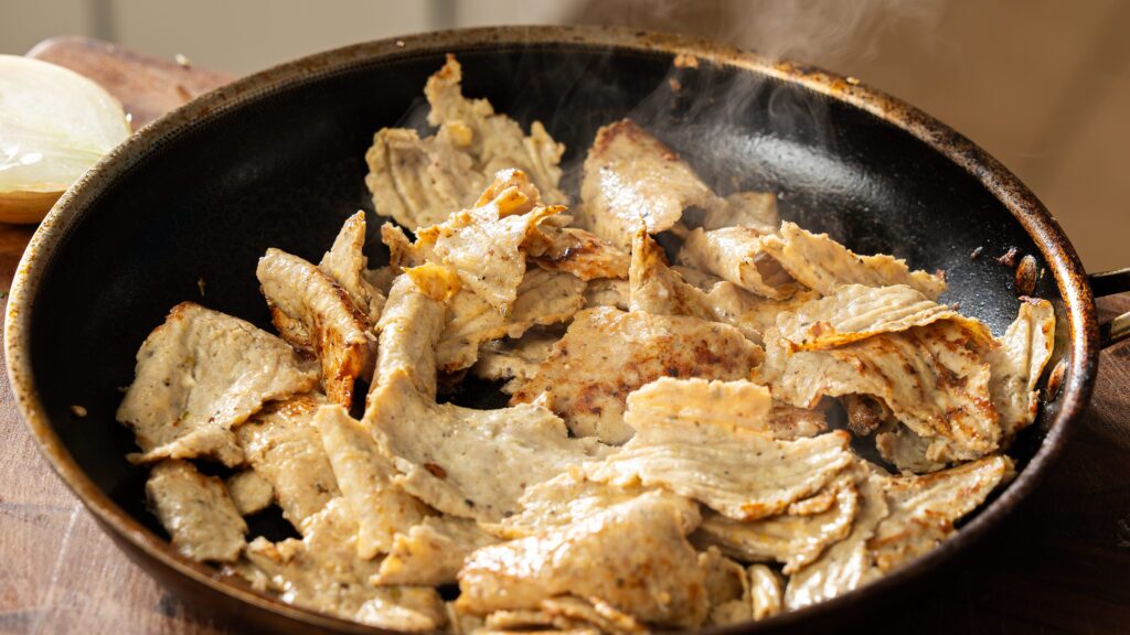 Crisping the chicken doner meat in a frying pan for the ultimate doner recipe.