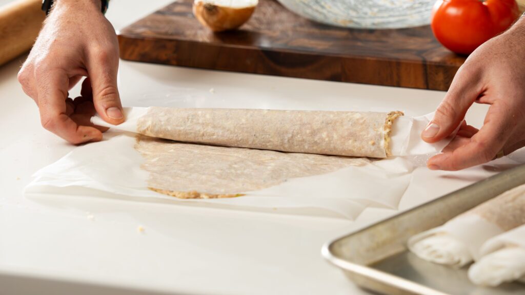 Rolling chicken doner between sheets of parchment for the ultimate doner recipe.