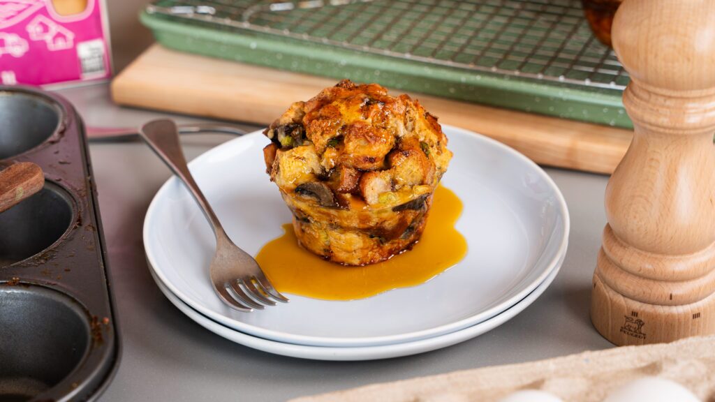 Savoury breakfast muffin on a plate with maple syrup on top.