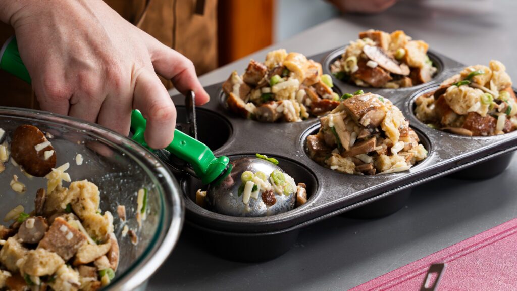 Packing savoury breakfast muffins into a muffin tin.