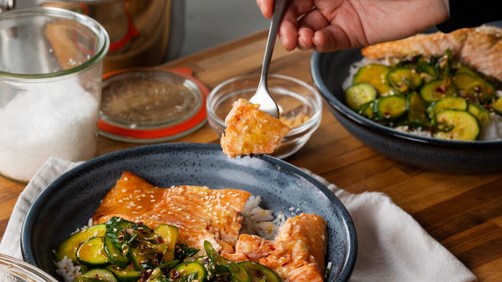 Taking a bite of a brown sugar salmon and cucumber bowl.
