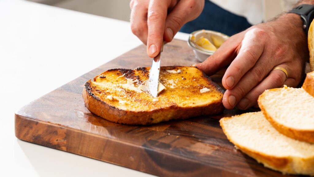 Adding butter to a slice of cottage cheese bread.