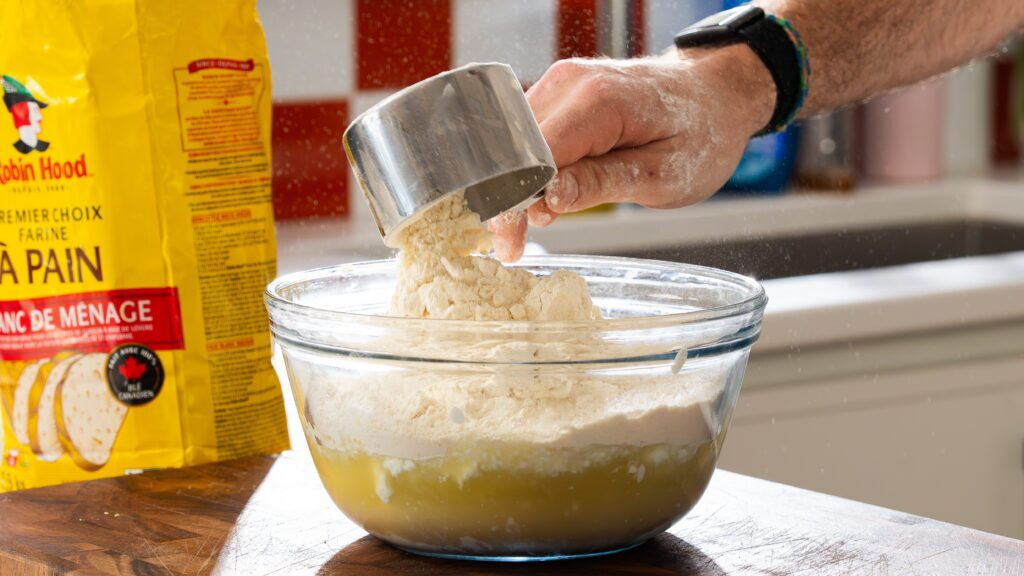 Adding flour to a bowl to make cottage cheese bread.