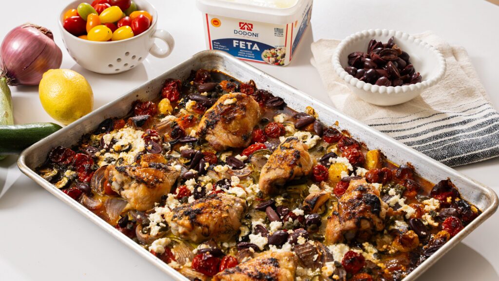 Greek chicken on a sheet pan with feta, vegetables and herbs.