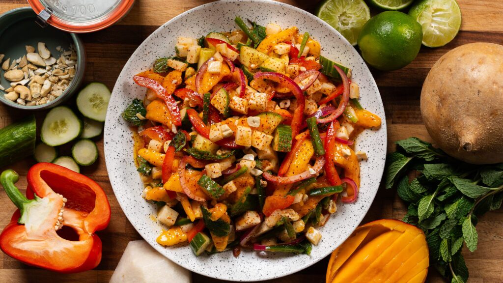 Jicama salad in a bowl with mango, cashews ands pickled red onion.