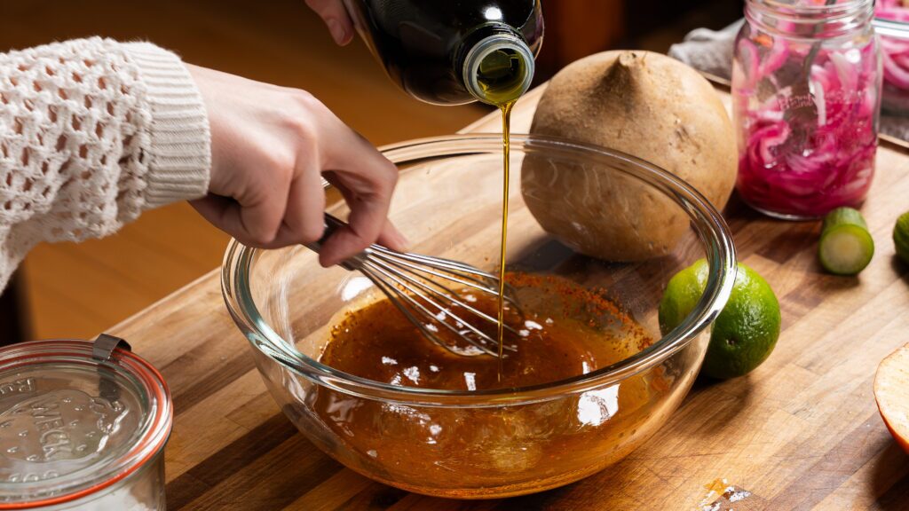 Whisking a dressing together in a mixing bowl to make a jicama salad recipe.
