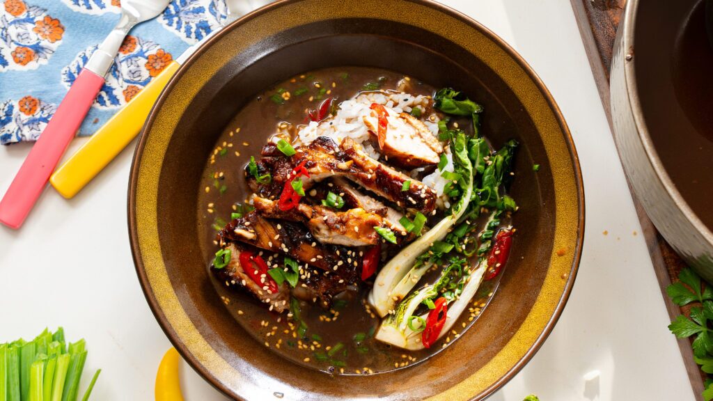 Brothy chicken and rice in a bowl with veggies and box choy.