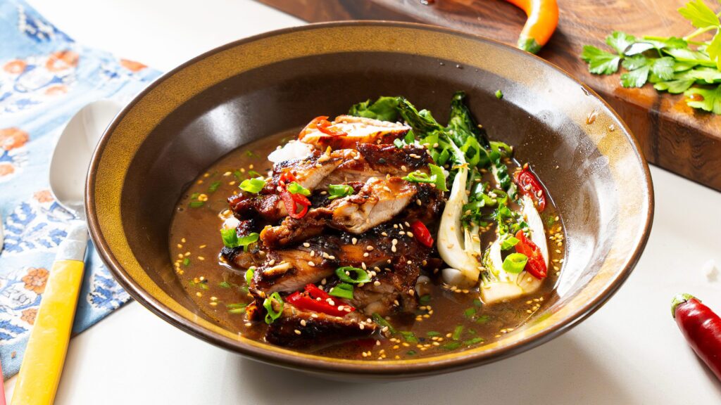 Brothy chicken and rice in a bowl with wok chop and other vegetables.