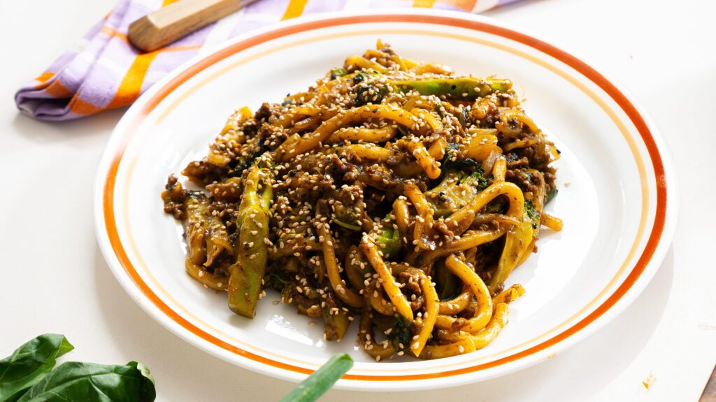 Serving bowl filled with steaming curry udon, topped with fresh basil, sesame seeds, and green onions for a comforting udon noodle recipe.