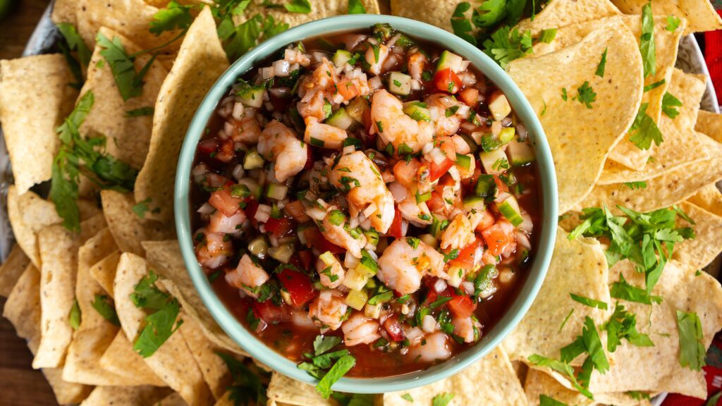 Shrimp cocktail in a bowl, surrounded by tortilla chips.