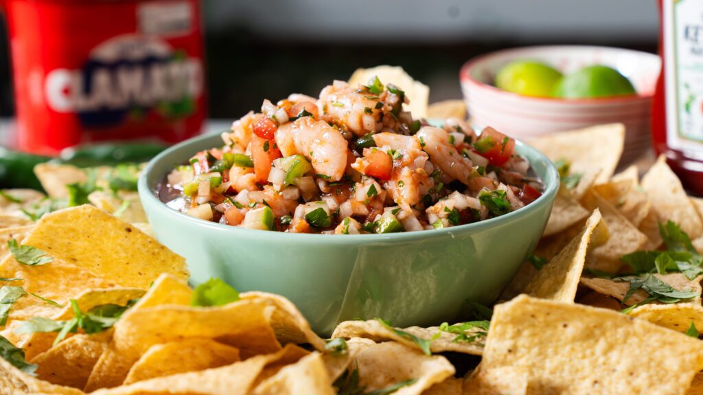 Shrimp cocktail in a bowl, surrounded by tortilla chips.