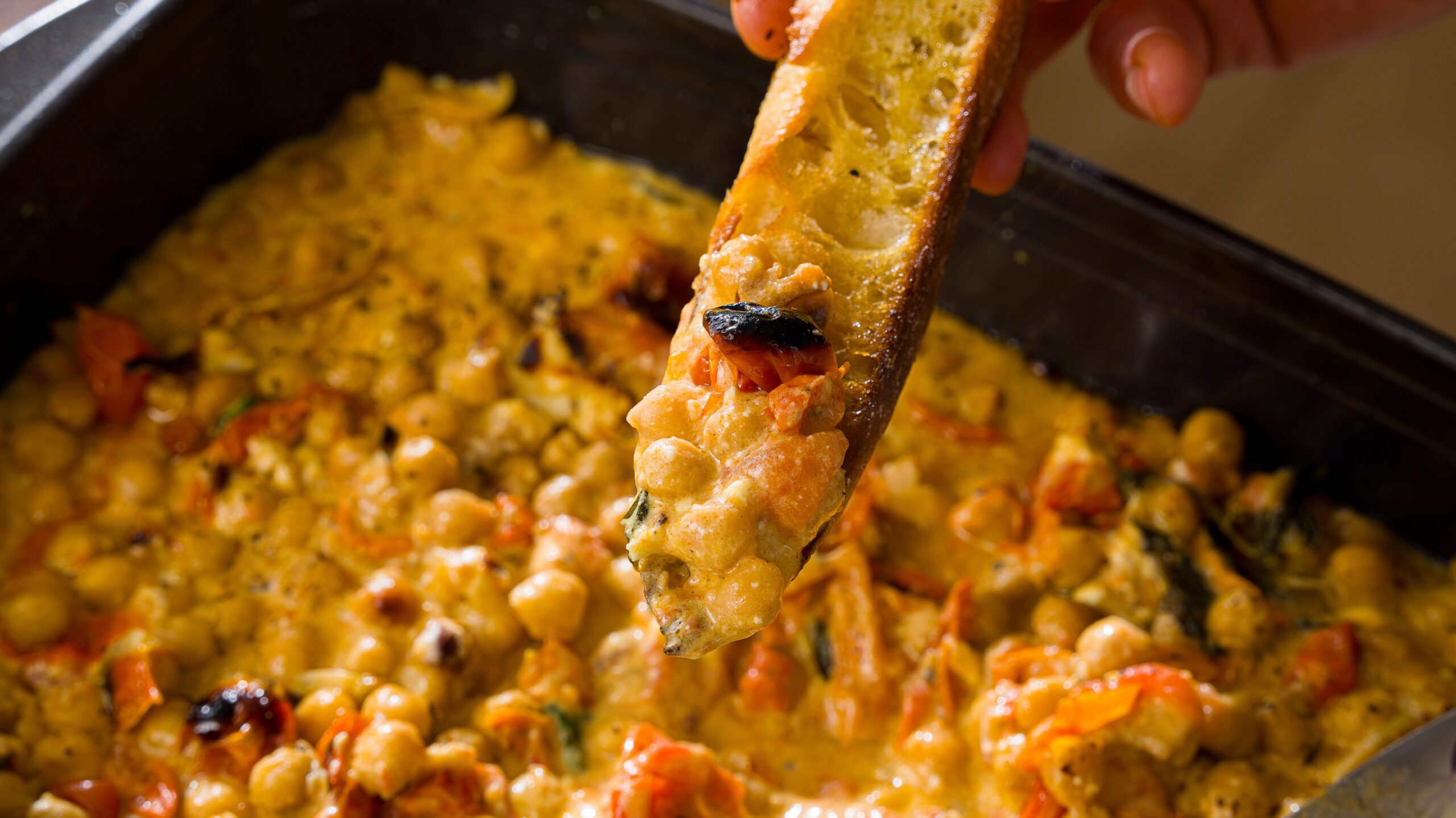 Bread sopping up a baked chickpeas and tomato recipe.