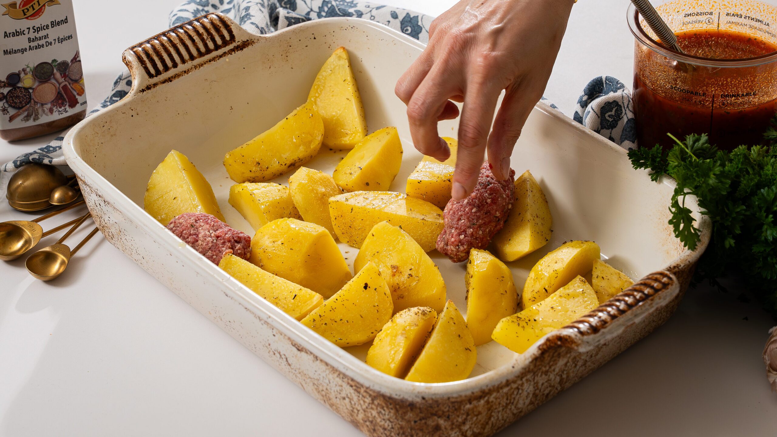 Nestling meatballs into a dish with potatoes for a Greek meatball recipe.