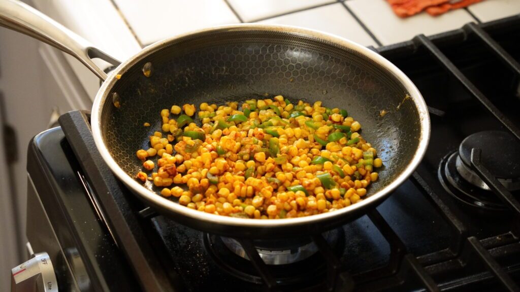 Saut&eacute;ing corn salad ingredient in a pan.