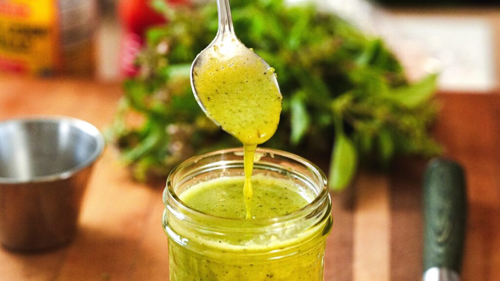 Adding a jalapeño vinaigrette to a mason jar.