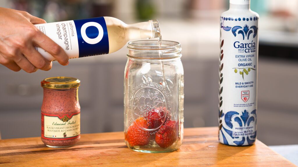 Adding vinegar to this strawberry salad dressing.