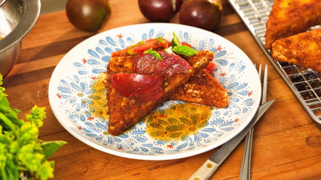Fried tofu with tomatoes on a plate.