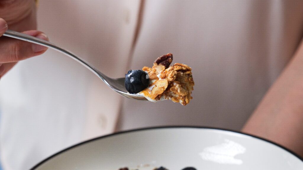 A scoop of Greek yogurt parfait with gluten free granola and blueberries.