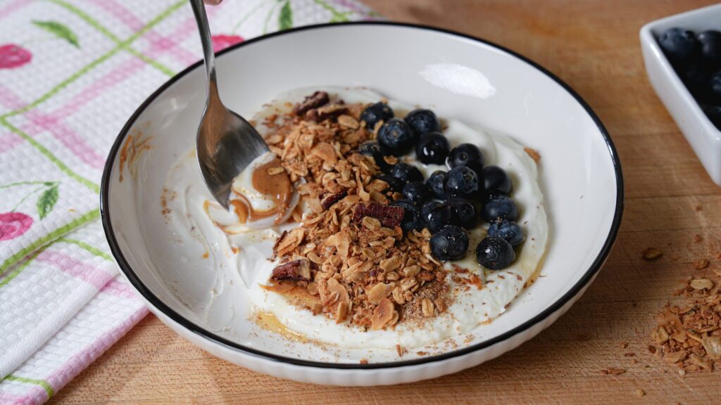 Greek yogurt parfait with gluten free granola and blueberries on a white bowl.