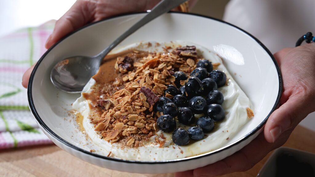 Greek yogurt parfait with gluten free granola and blueberries on a white bowl.