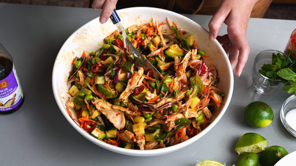 Adding rotisserie chicken to a bowl for a delicious chicken salad recipe.