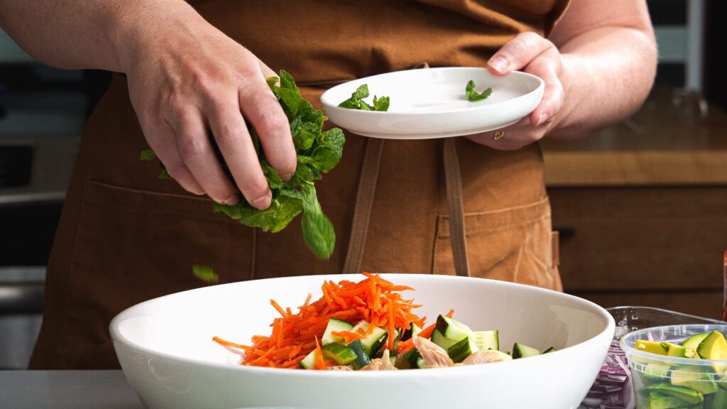 Adding fresh mint to a rotissirie chicken salad.