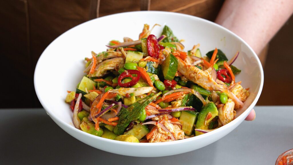 A rotisserie chicken salad in a white bowl.