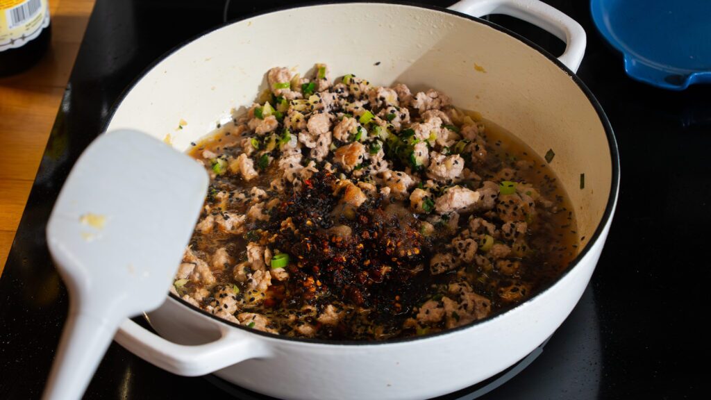 Pork and vegetables being cooked in a pot for a delicious pork dumpling bowl recipe.