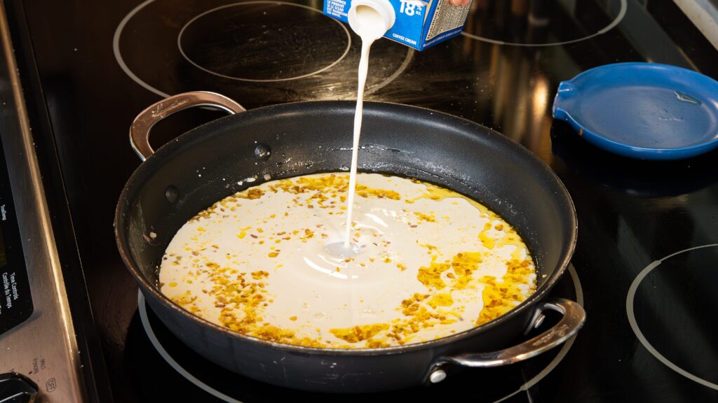 Adding cream to a skillet for an easy gnocchi recipe.
