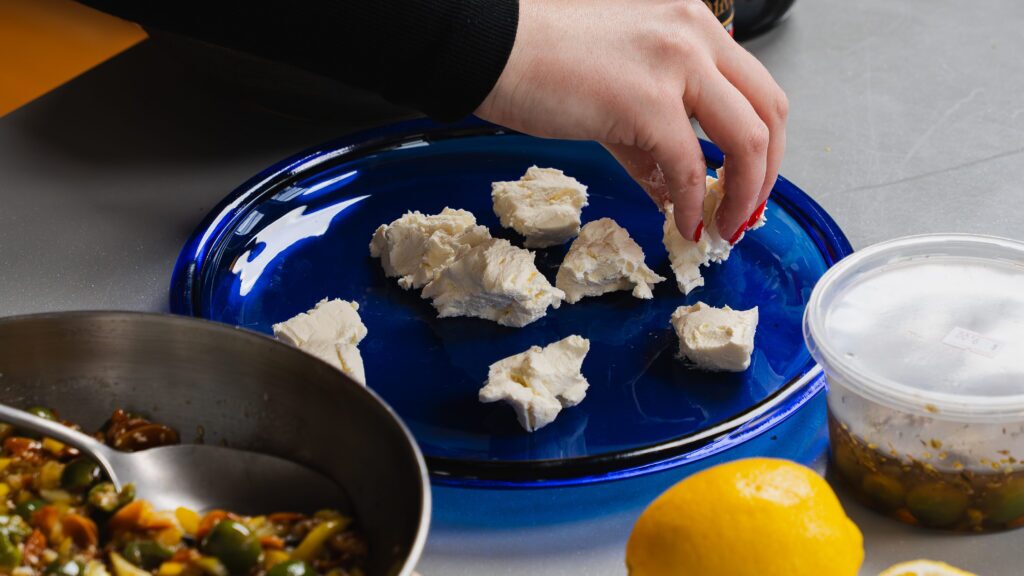 Adding cream cheese to a plate to make a delicious olive dip recipe.