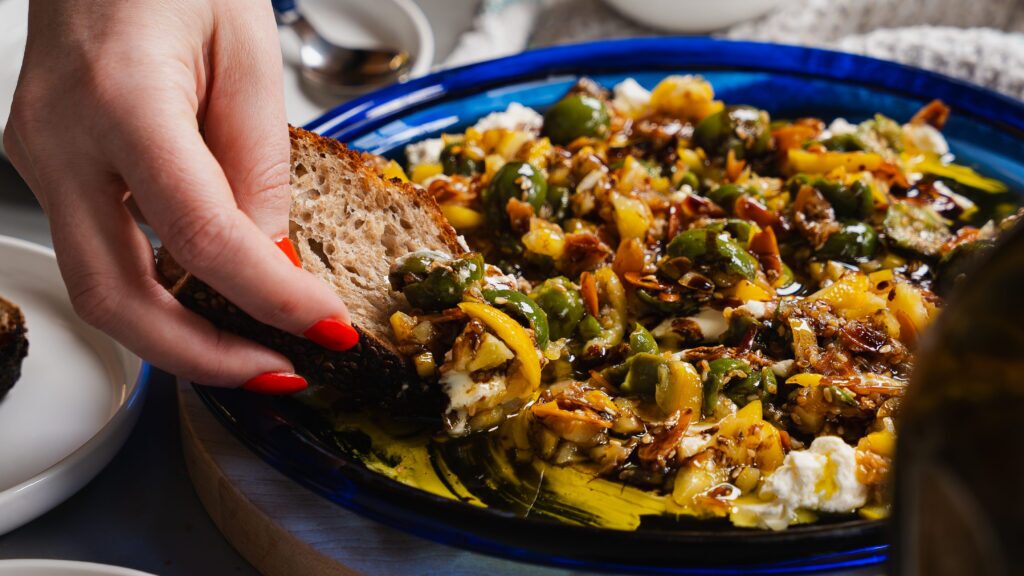 Dipping a slice of bread into this cream cheese and olive spread with honey & lemon.
