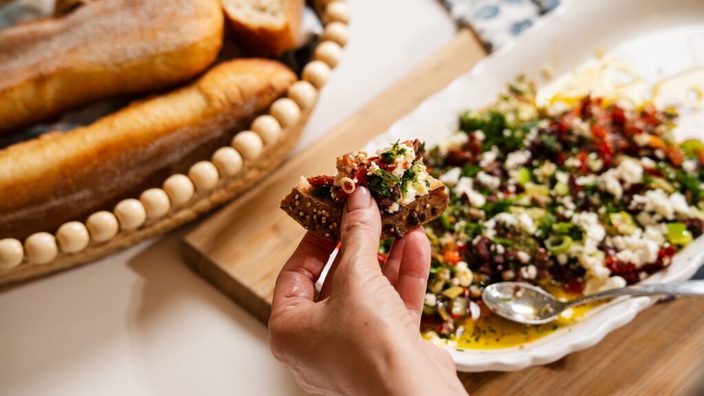 Scooping up this olive oil bread dip with a piece of crusty bread.