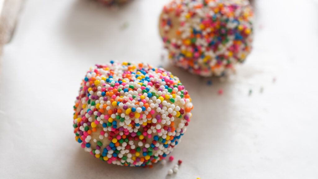 A ball of Sprinkle Cookies on a sheet tray. 