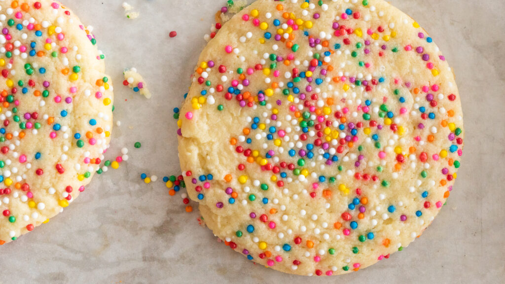 A close up shot of Sprinkle Cookies on a parchment paper lines tray. 