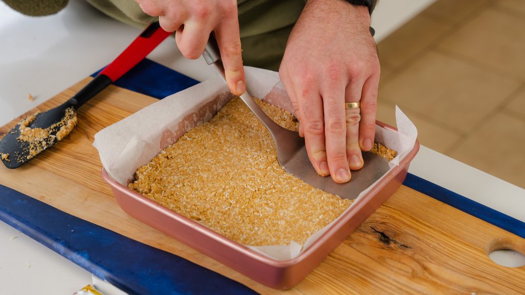 pushing down the crust in a pan for the recipe