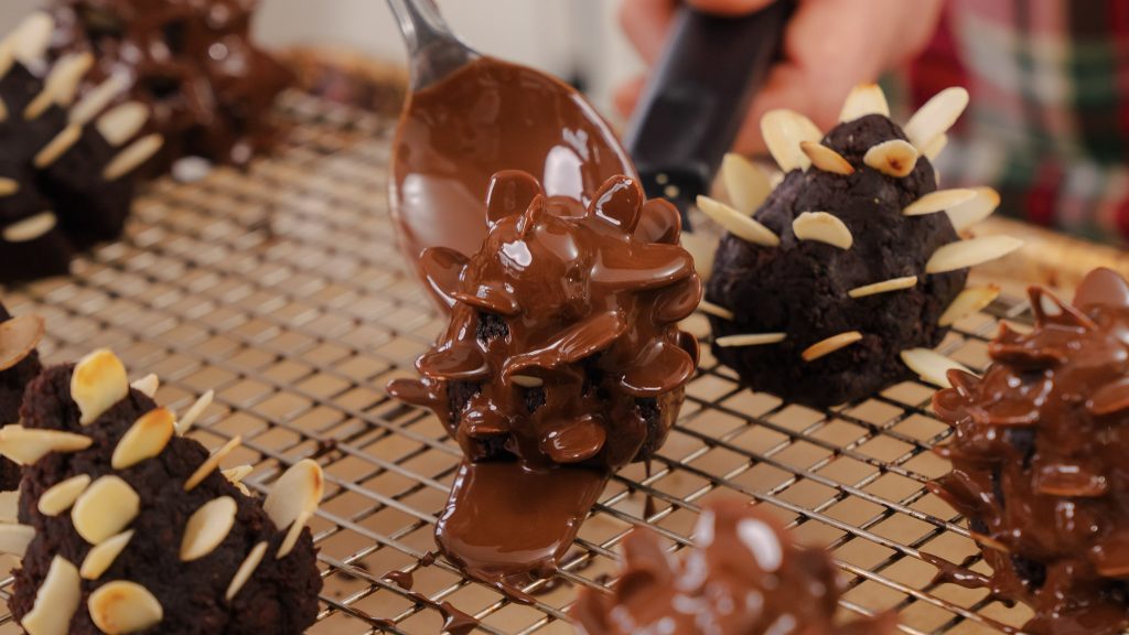 A close up shot of Chocolate Brownie Almond Pinecones being covered in melted chocolate.