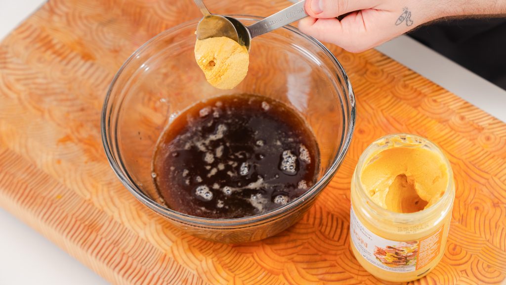 the process of Brown Butter Vinaigrette being made. Dijon mustard is being added to a large bowl of butter. 