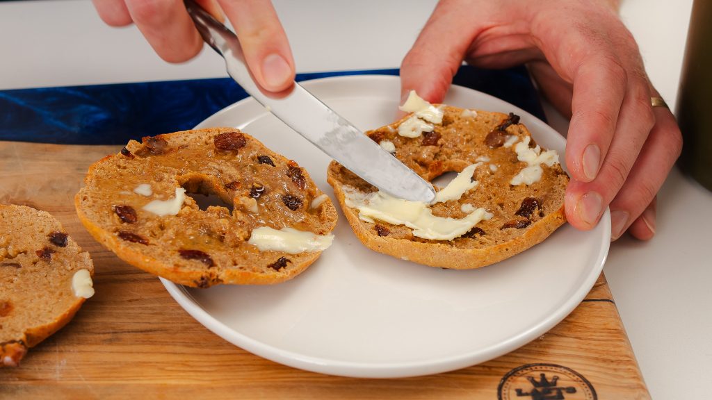 A close up shot of Andy spreading butter on a Gluten-Free Bagels. 