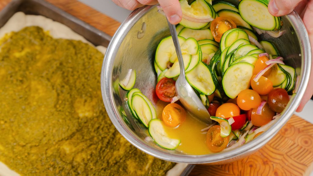 The veggies for the pizza are being marinated in olive oil and salt. 