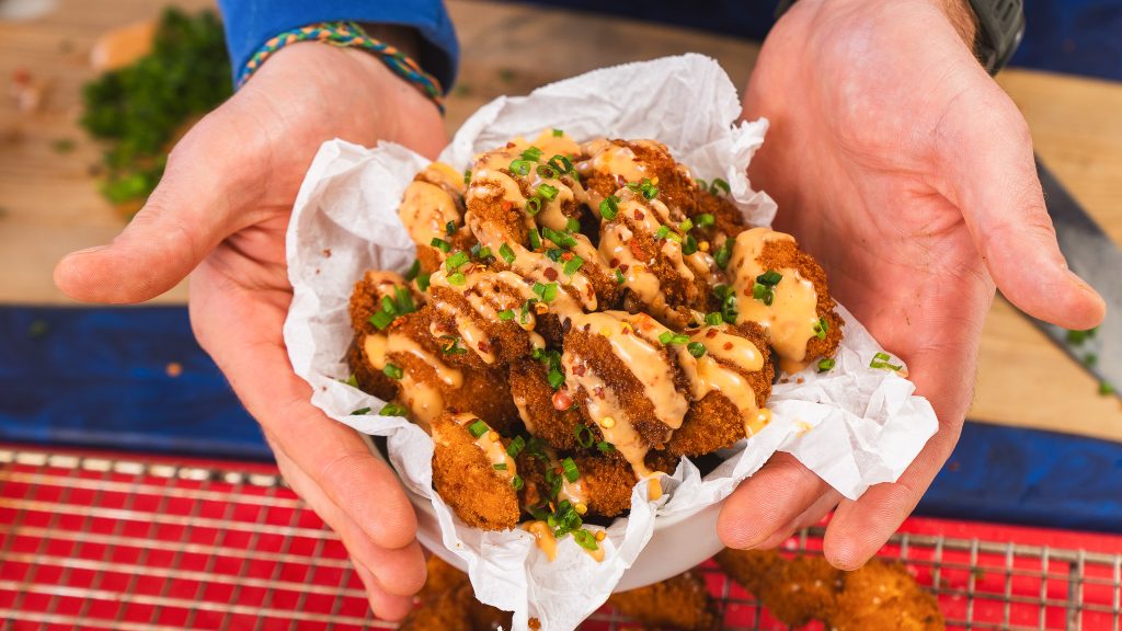 Andy holding a bowl of Bang Bang Chicken. There is crumpled parchment paper lining the bowl. 