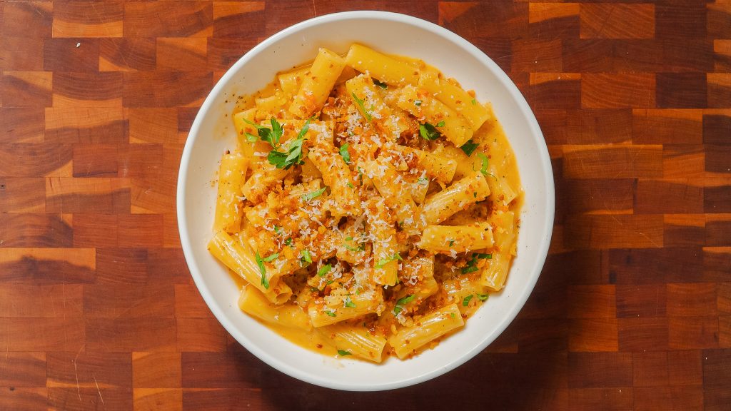 Caramelized Onion Pasta in a white bowl, on a wooden countertop.