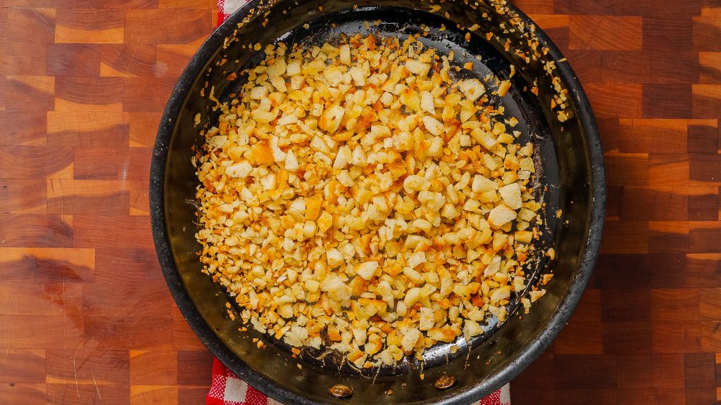 A frying pan with homemade breadcrumbs— one of the steps to a delicious caramelized onion pasta dish.