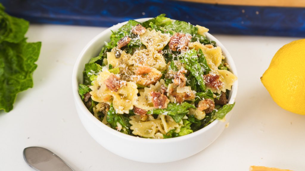 A close up shot of Caesar Pasta Salad in a white bowl.