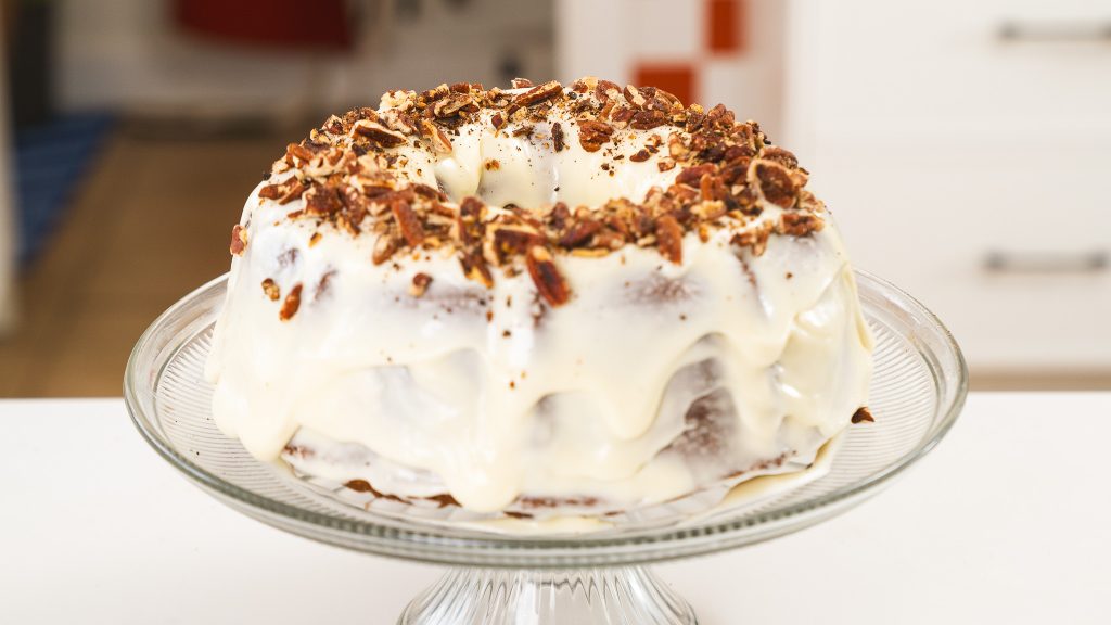 A close up shot of a fully made Carrot Bundt Cake, with icing and nuts