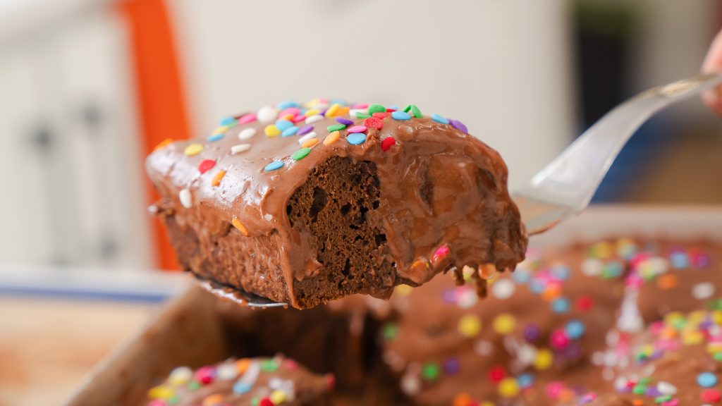 A close up shot of Cosmic Protein Brownies. The chocolate icing and sprinkles are oozing over the side. 