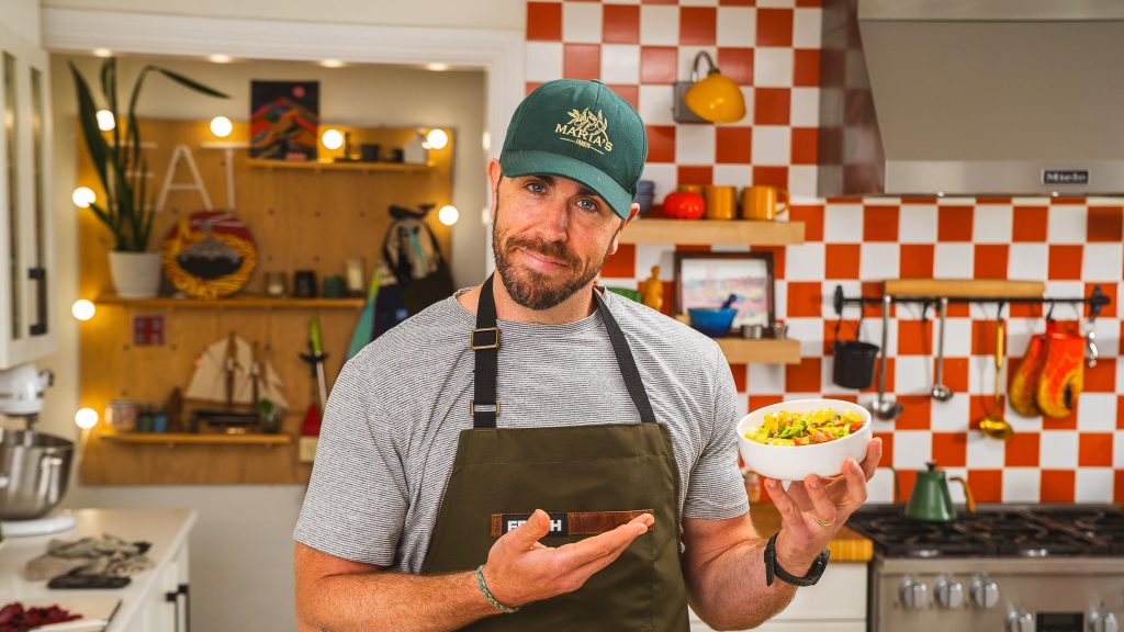 andy hay holding a bowl of salad pointing with his finger